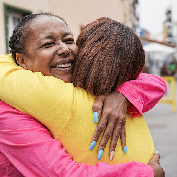 Middle aged woman smiling and hugging friend
